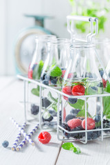 Sparkling soda in bottle with raspberries, blueberries and blackberries