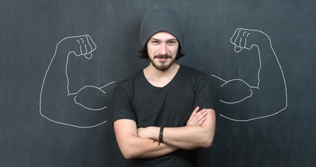 Fototapeta na wymiar Young man against the background of depicted muscles on chalkboard