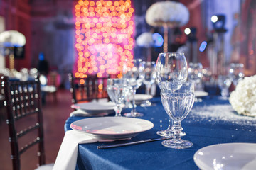 Wedding. Banquet. The chairs and table for guests, served with cutlery and crockery and covered with a blue tablecloth.