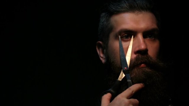 Sharp scissors, dangerous games of the bearded man. Beauty salon or barbershop. Bearded man plays a game with blade. Attractive hairdresser with beard