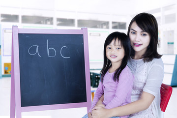 Teacher teaches alphabet to student in classroom