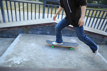young skateboarder legs riding skateboard at skatepark