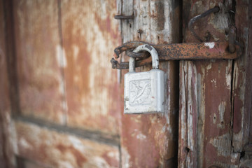 The old door locked with a padlock hanging brackets. At an angle, soft focus