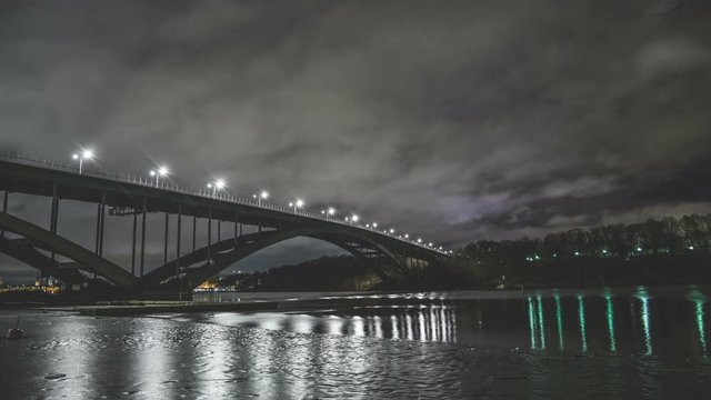 Time Lapse of arch bridge and river at night. Fast moving clouds and ice in the water