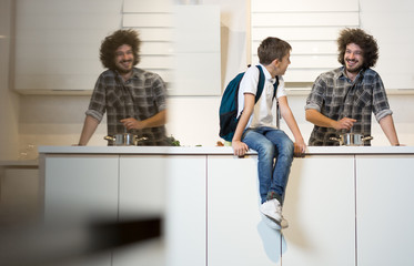 Happy father preparing meal to son in kitchen. Father preparing son for school