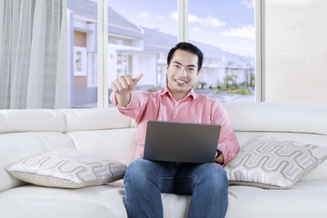 Fototapeta premium Young Asian person with laptop on couch