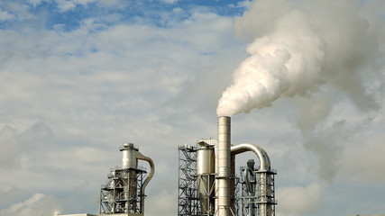 Obraz premium Factory smoke stack and pipes puff into air. Atmospheric air pollution industrial scene. Non-ecological and non-sustainable manufacturing.