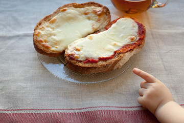 The hand of a little boy who is trying to steal my father's sandwich with tea.