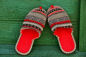 Разноцветные домашние тапочки на зелёной,деревянной стене