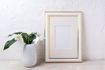 Gold decorated frame mockup with tender white lily in vase
