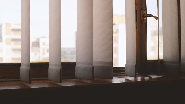open window and the wind. vertical blinds in the room swaying in the wind