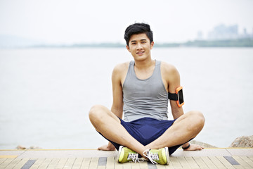 Fototapeta na wymiar young asian man taking a break during outdoor exercise