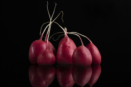 Seven fresh juicy radishes on black background