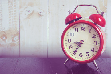 Red clock on wood background.