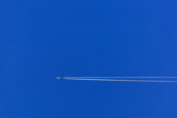 Jet airplane with white trail against the blue sky
