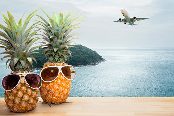 pineapple with sunglasses on tropical sea and airplane background,concept summer and travel...