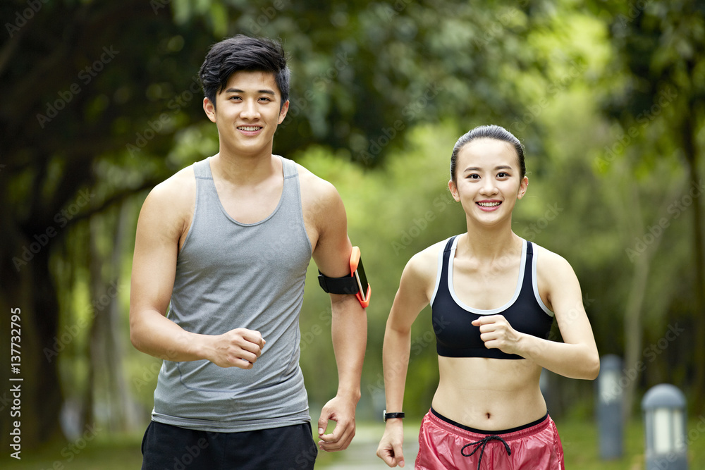 Wall mural young asian couple running jogging in a park