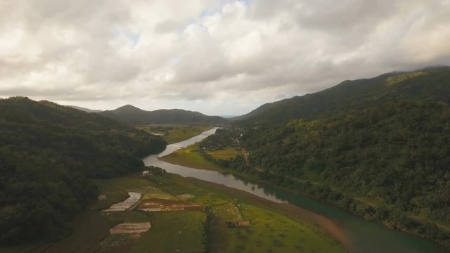 Aerial view: river and mountain, hills. Mountain river flows through green forest. Tropical river in the rain forest in Asia. 4K video. Aerial footage. Landscape.