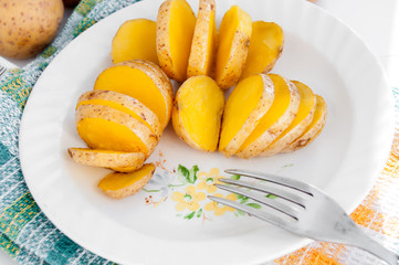 Baked potatoes in their skins yellow on a white plate