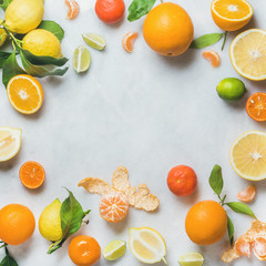 Variety of fresh citrus fruit for making juice or smoothie over light grey marble table background,...