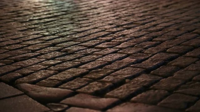 People walking on a cobblestone street  by colourful neon street lights
