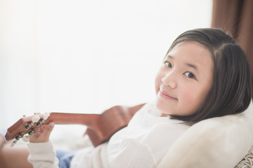 Obraz na płótnie Canvas Asian girl playing ukulele at