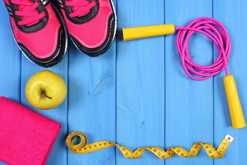 Pair of sport shoes, fresh apple and accessories for fitness on blue boards, copy space for text