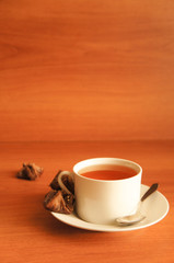 White cup of tea on wood background with little cookies 