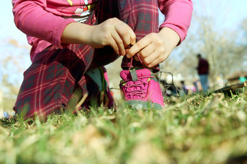 small gir tying shoelaces outdoor