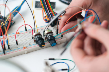 Hands connecting wires to breadboard closeup. Engineer constructing new gadget. Electronic development, diy, hobby, education concept