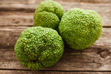 Several green osageorange on wood closeup. Group or tropical fruits on old wooden table. Exotic, gourmet, delicious sweet concept
