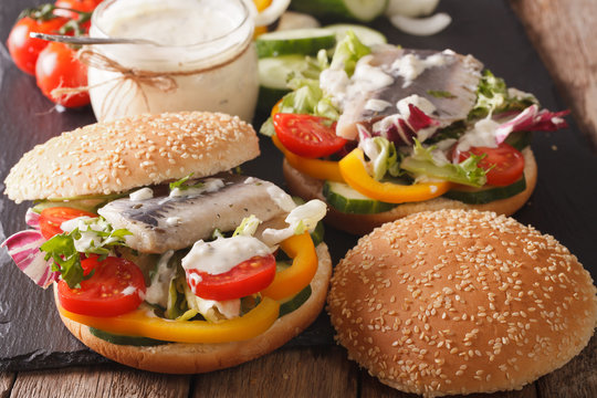 Fishburger with herring, gravy and fresh vegetables close-up. Horizontal
