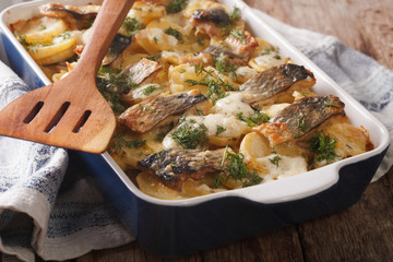 casserole of potatoes, herring in cream sauce in baking dish. horizontal