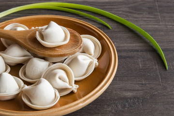 Frozen homemade dumplings on the wooden board in the kitchen. Healthy eating and lifestyle.