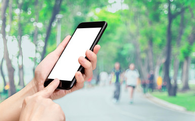 Hand click mobile phone with blur people exercise at park background bokeh light,White screen mock up template for adding your design or your text