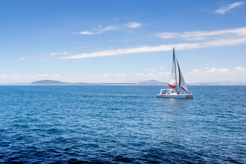 Naklejka premium View of sailing boat on Atlantic Ocean near Robben Island, South African coast