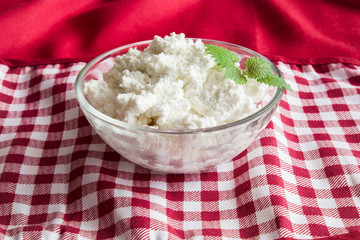 Cottage cheese in the dish on the wooden table in the kitchen. Healthy eating and lifestyle.