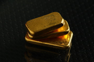 The gold bars put on the dark and gross surface background  represent the business and finance concept related idea. 