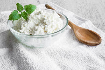 Cottage cheese in the dish on the wooden table in the kitchen. Healthy eating and lifestyle.