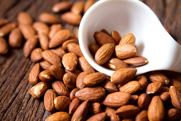 close up Peeled almonds nut  in small white cup on wooden  background