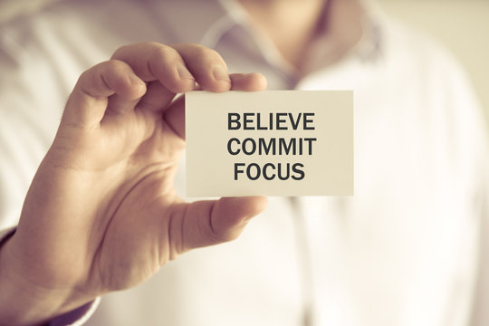 Businessman holding BELIEVE, COMMIT, FOCUS message card