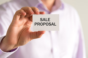 Businessman holding card with text SALE PROPOSAL