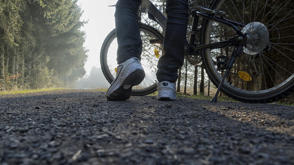Young male legs with sneakers and bike on forest trail - obrazy, fototapety, plakaty