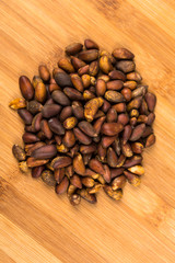 Organic unhulled pine nuts isolated on a wood background