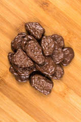 Milk chocolate banana chips isolated on a wood background