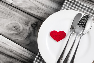 red heart shape with White empty plate with fork and spoon on wooden table for love dinner concept