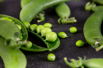 fresh green sweet peas  on black stone background
