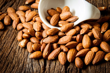 close up Peeled almonds nut  in small white cup on wooden  background
