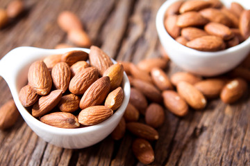 close up Peeled almonds nut  in small white cup on wooden  background