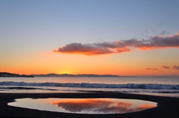 Fototapeta na wymiar 日の出寸前の江の島海岸 朝焼けの茜色の空が海岸の水溜りに映って美しかった。